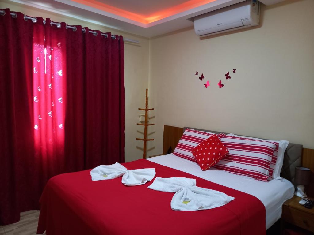 a bed room with a red bedspread and red pillows at Quartos Em Casa Caxias - Pousada Paraíso in Duque de Caxias