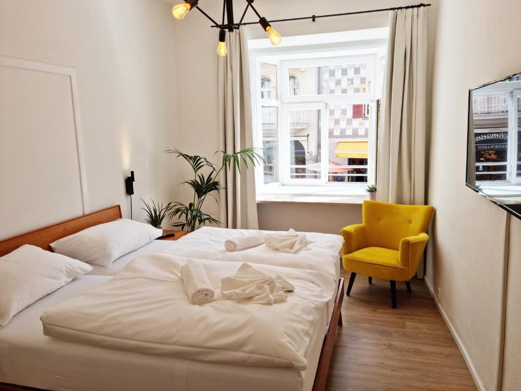 una camera con due letti e una sedia gialla di Rosa Rooms Meran a Merano