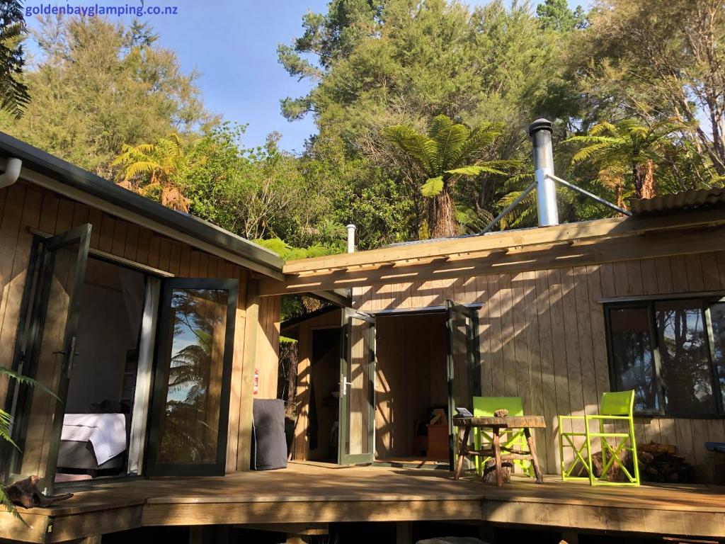 a house with glass doors and a table on a deck at Golden Bay Glamping in Takaka
