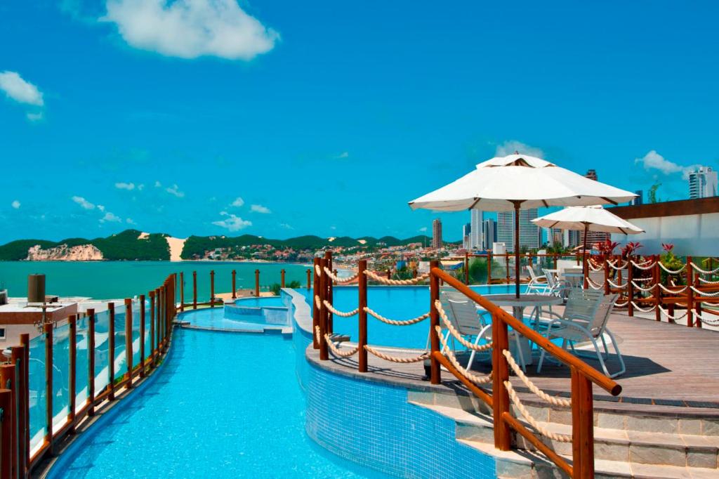 a pool at a resort with chairs and umbrellas at Pontalmar Praia Hotel in Natal