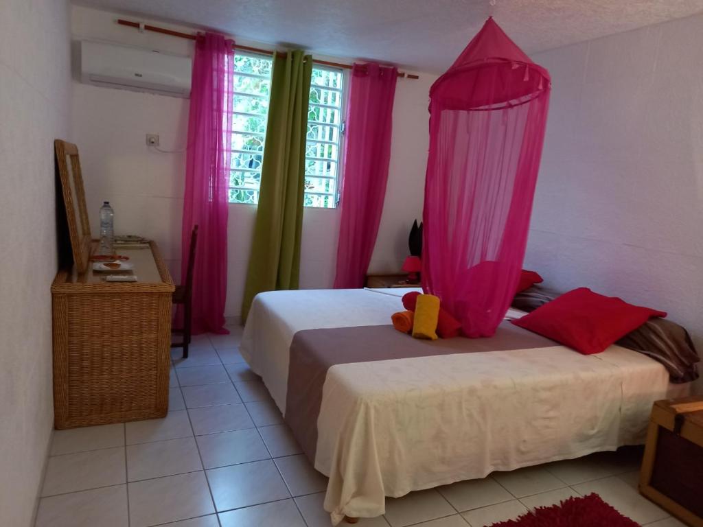a bedroom with two beds and pink curtains at Mapi des Iles - chambre chez l'habitant in Le Gosier