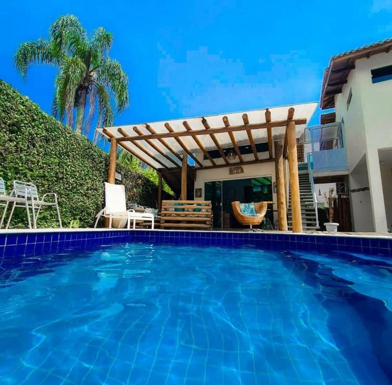 a swimming pool in front of a house with a pergola at Mares de Camburizinho in Camburi