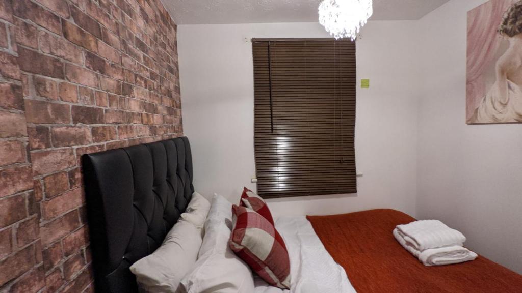 a room with a bed with a brick wall at Stunning 1 bedroom apartment in Dagenham in Dagenham