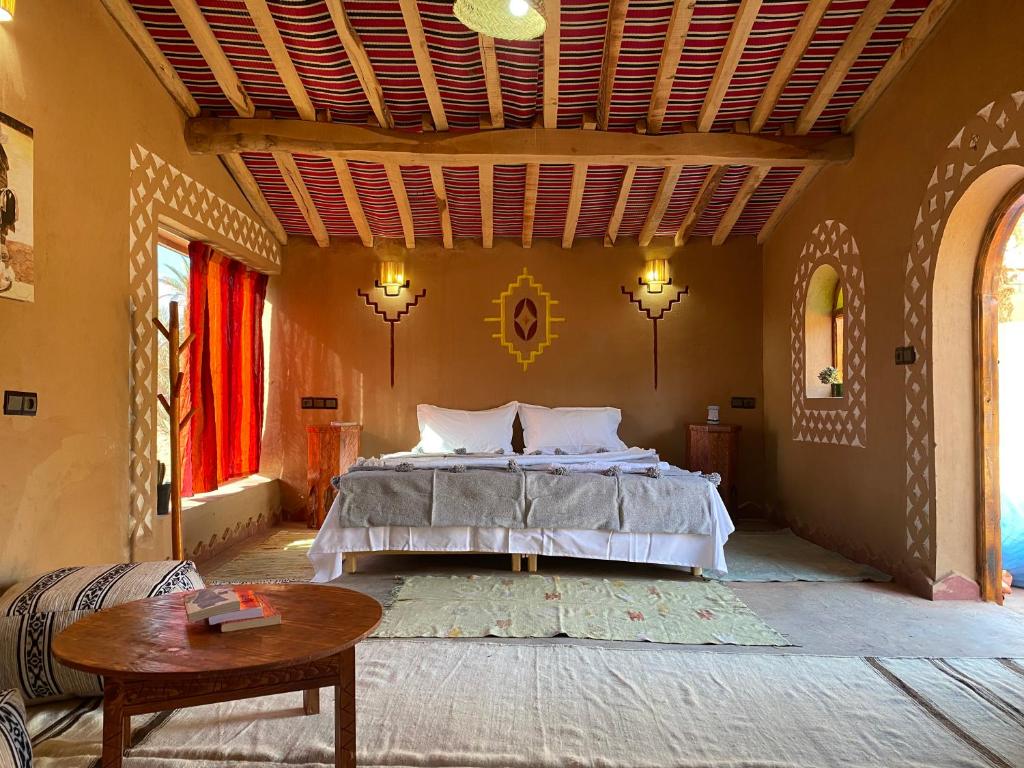 a bedroom with a bed and a table at Camp Auberge Sahara Marokko in Mhamid