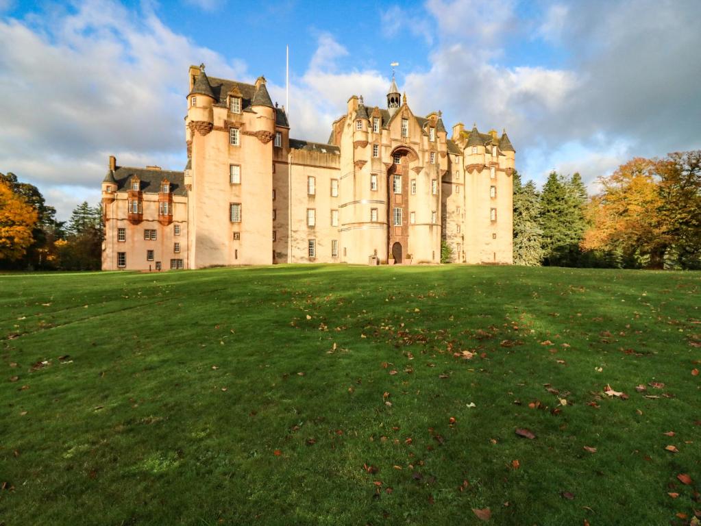 un vieux château sur un grand champ herbeux dans l'établissement The Preston Tower Apartment - Fyvie Castle, à Turriff