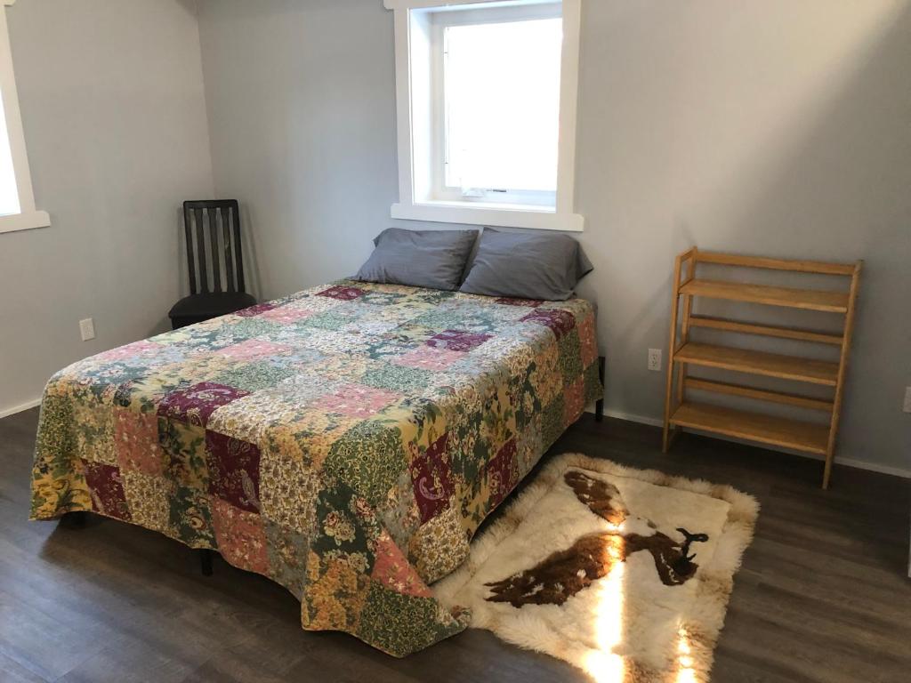 a bedroom with a bed with a quilt and a dog on a rug at Copperville B & B in Glennallen