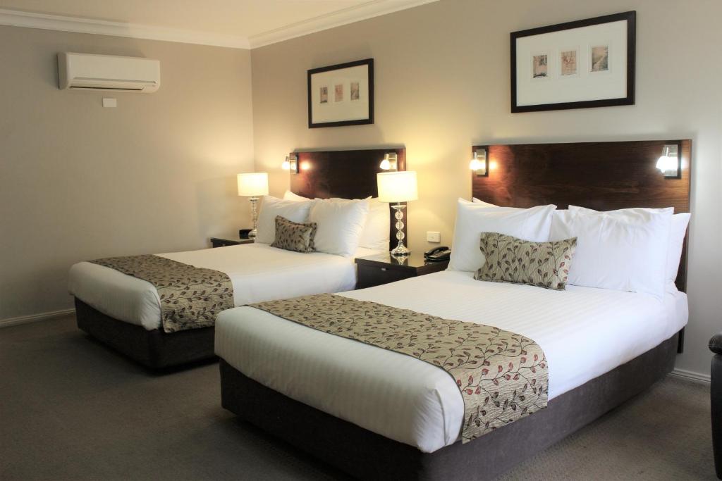 Habitación de hotel con 2 camas y 2 lámparas en Carlyle Suites & Apartments, en Wagga Wagga