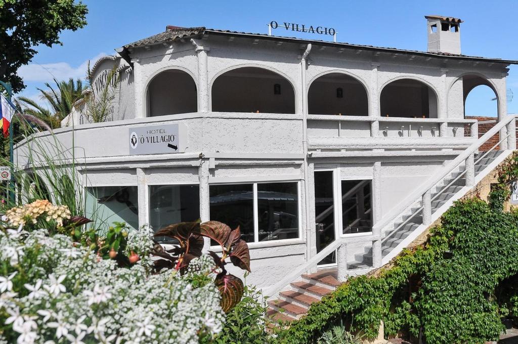 - un bâtiment blanc avec une véranda et des fleurs dans l'établissement Ô Villagio Hôtel, à Villeneuve-Loubet