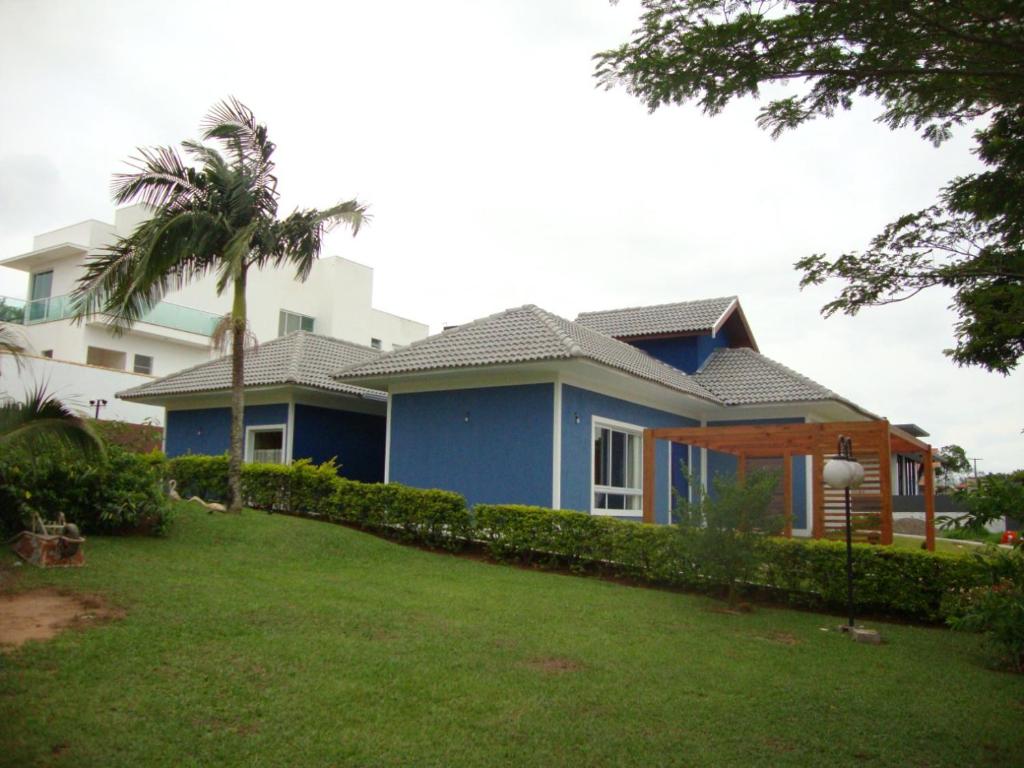 une maison bleue avec une pelouse devant elle dans l'établissement Minha Casinha Azul na Represa, à Paranapanema
