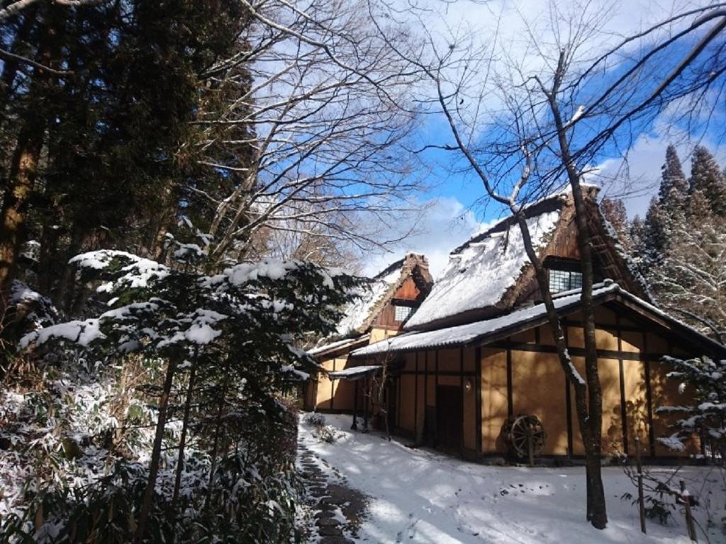 a house with snow on the roof of it at Wanosato in Takayama