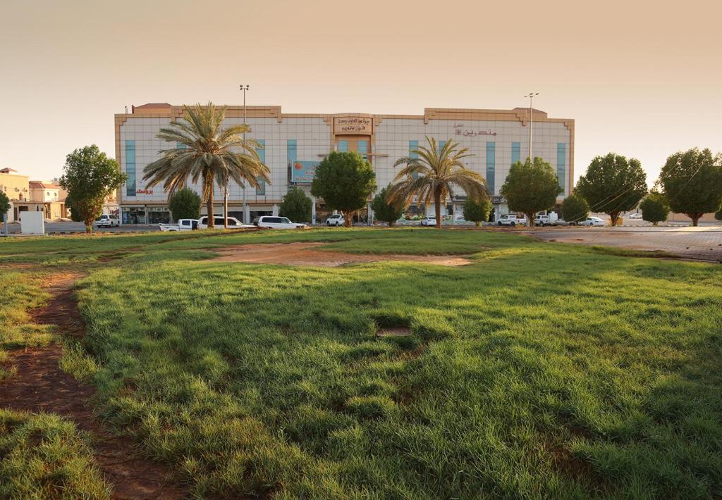 ein Grasfeld vor einem großen Gebäude in der Unterkunft Mandareen Al Sharq Serviced Apartments in Az Zulfi