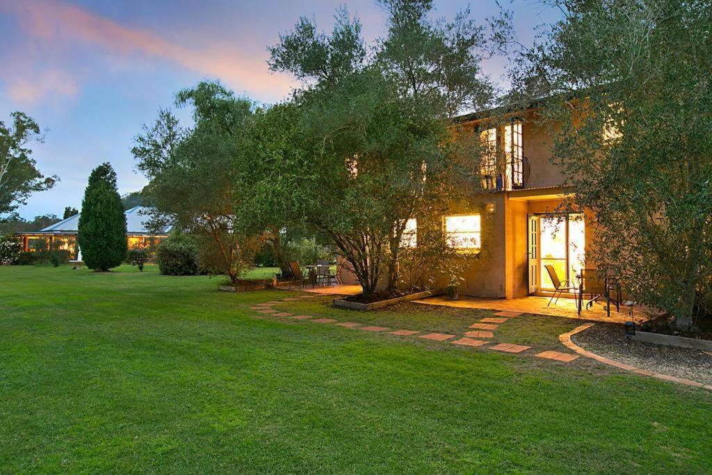 a house with a green yard in front of it at Chez Vous Split Level Balcony Spa Villa! in Pokolbin