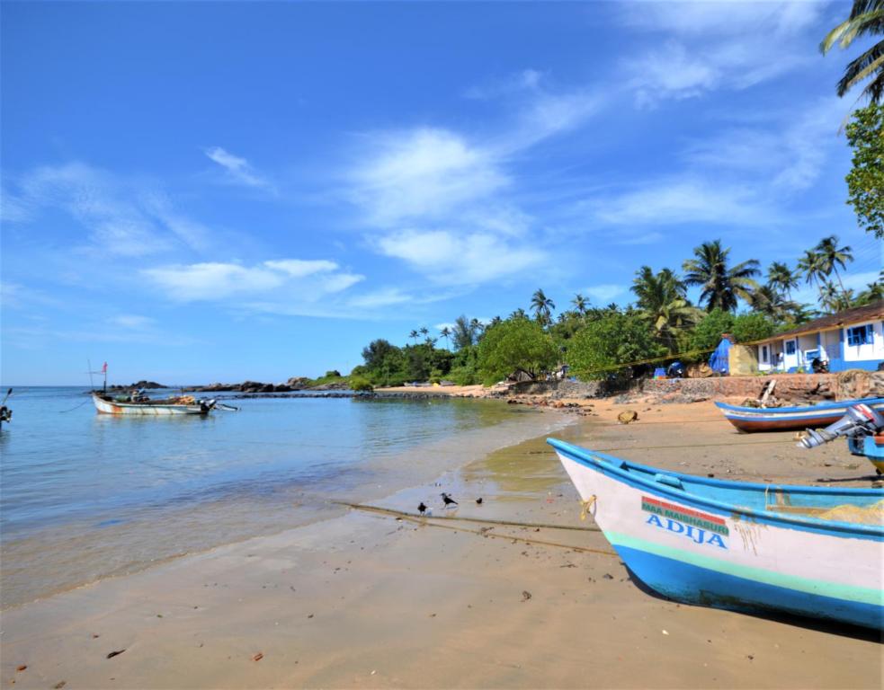 une plage avec deux bateaux assis sur le sable dans l'établissement Colomb Bay Homes, à Canacona