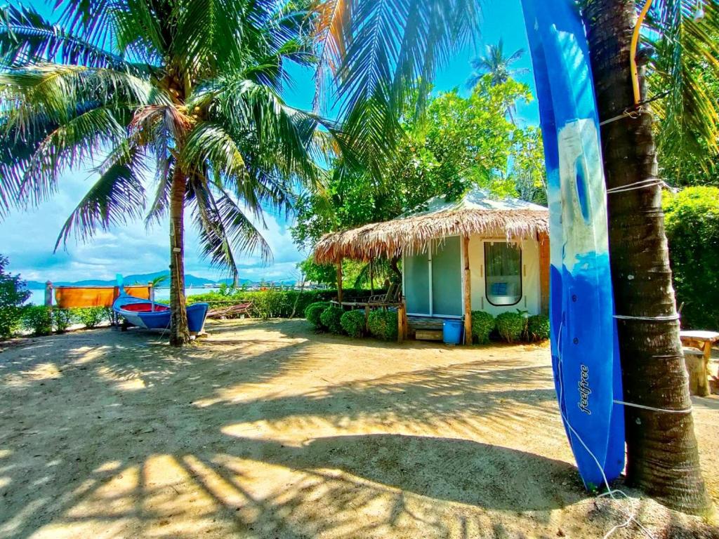 a blue surfboard in front of a house on the beach at Mook Montra Resort Sea Front in Koh Mook