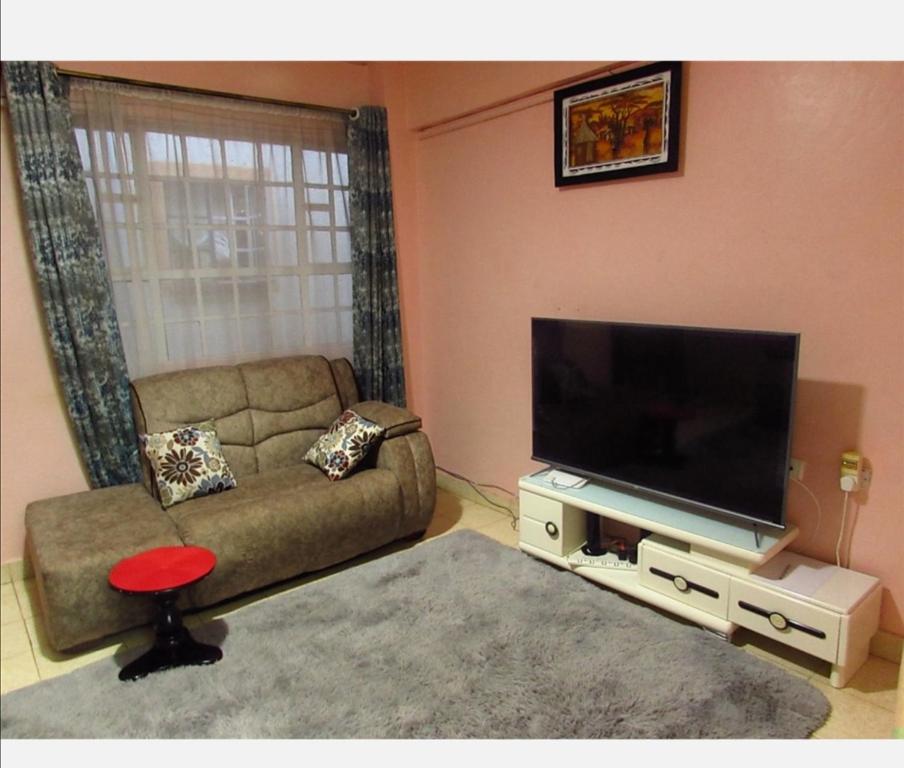 a living room with a couch and a flat screen tv at Tazama place in Nyeri