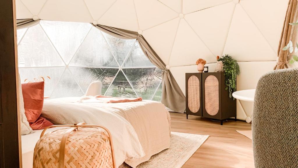 een slaapkamer in een tent met een bed en een bad bij Romantische glamping dome Koksijde - Duiniek in Koksijde