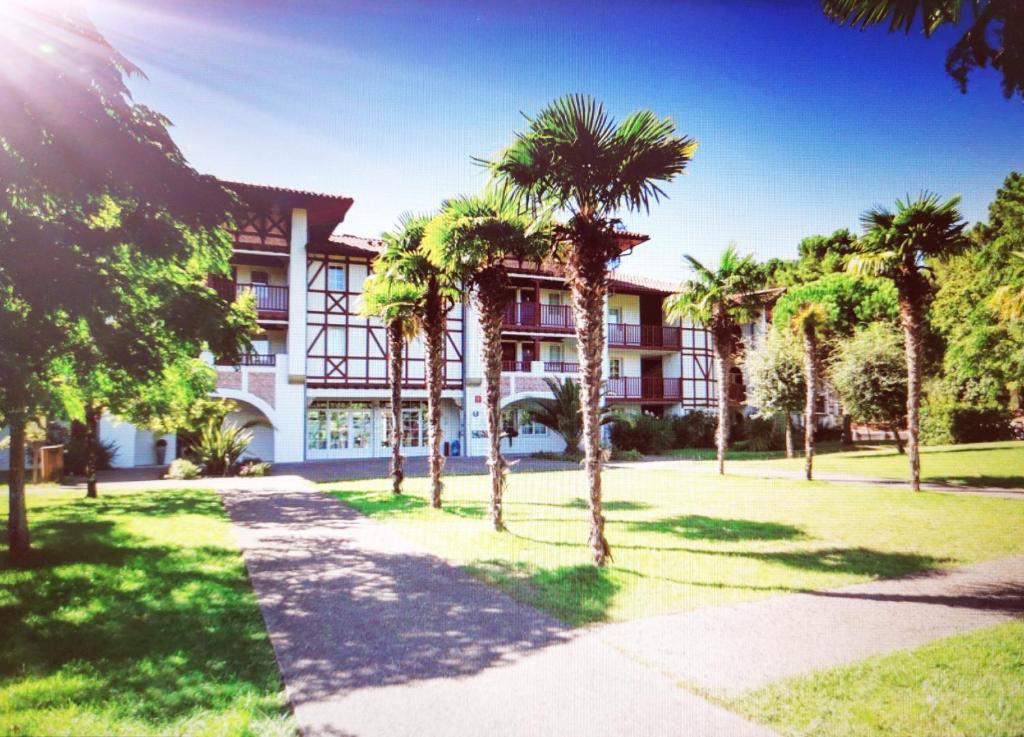 a building with palm trees in front of it at Appartements au coeur du golf, proche du lac et vélodyssée in Biscarrosse