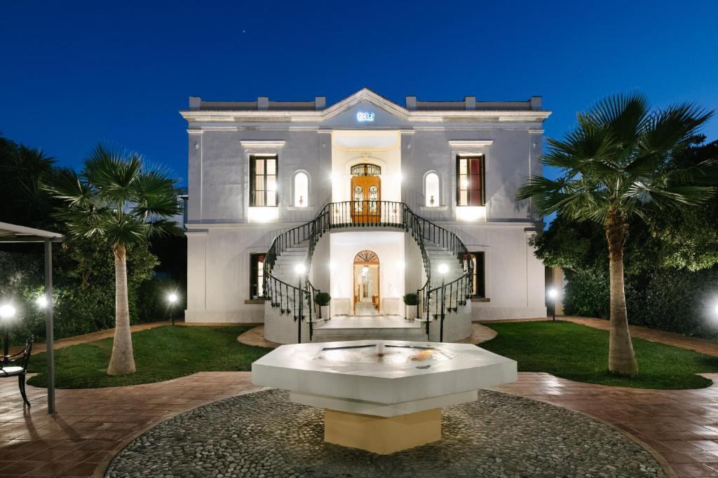 ein großes weißes Haus mit einem Brunnen davor in der Unterkunft Halepa Hotel in Chania