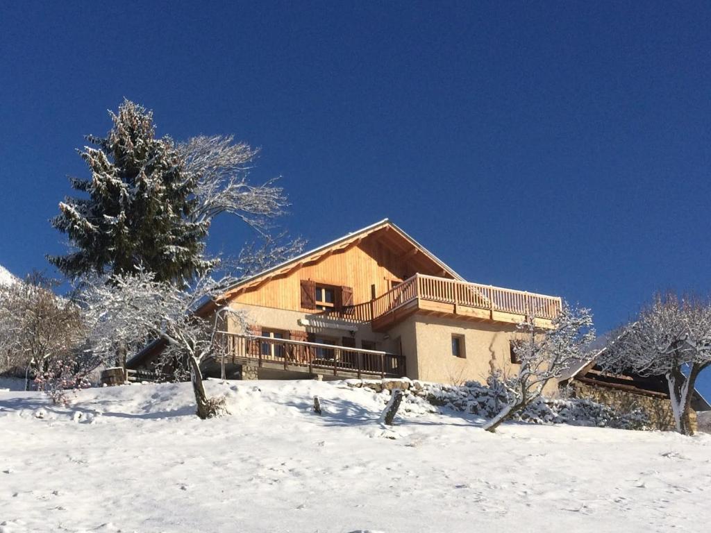 een huis op een besneeuwde heuvel met een boom bij La Rawette in Puy-Sanières