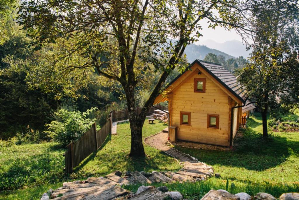 a small wooden cabin with a tree in a field at Mountain Lodge Jereka in Bohinj