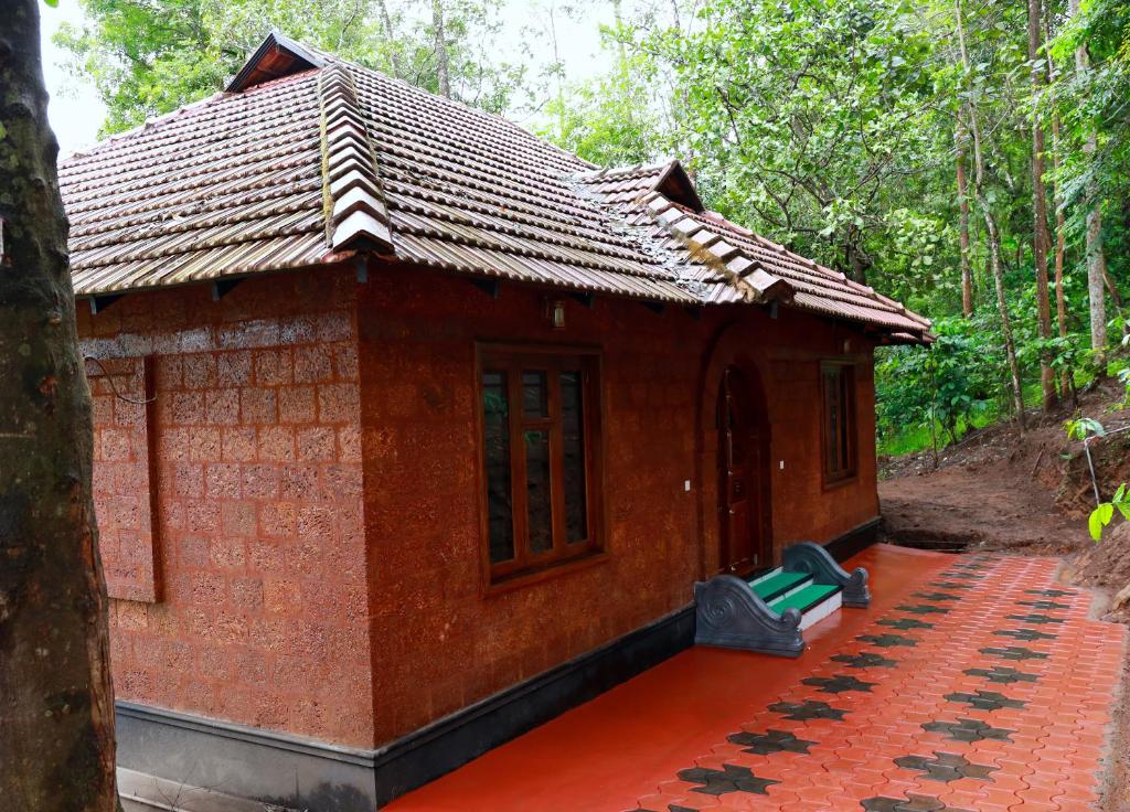 a small red brick building with a tile roof at Green Garden Holiday Home Wayanad in Vythiri
