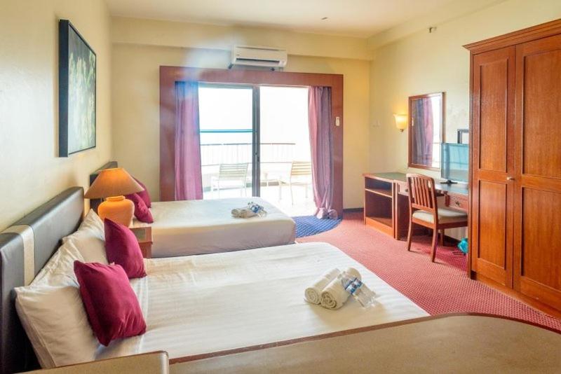 a hotel room with two beds and a desk at J Beach Suites At Rainbow Paradise in Tanjung Bungah