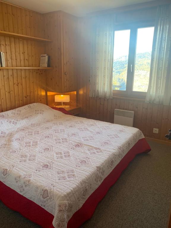 um quarto com uma cama com uma colcha em Appartement dans chalet em Les Collons