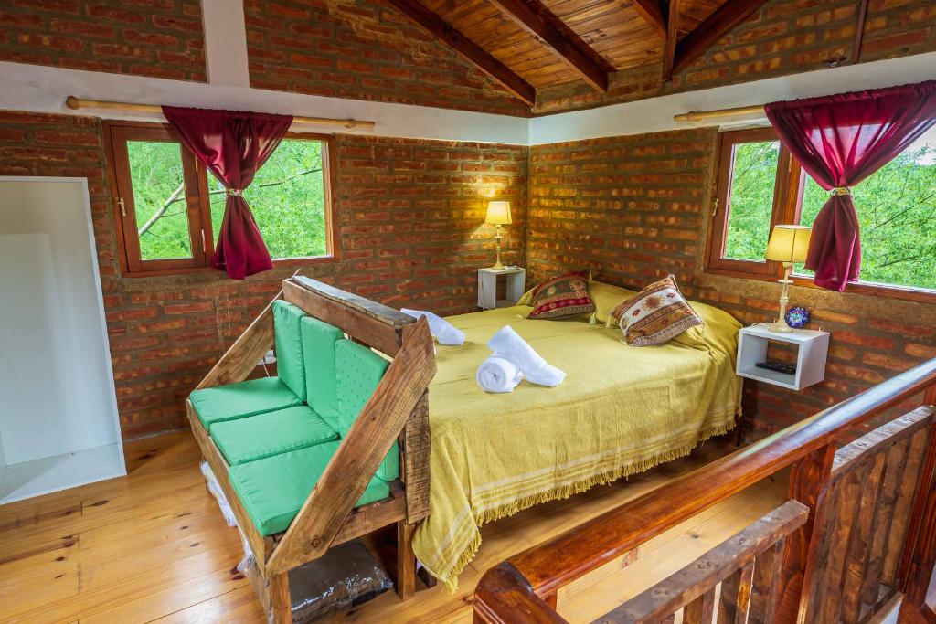 a bedroom with a bed and a green chair at Las del Tatu in El Bolsón