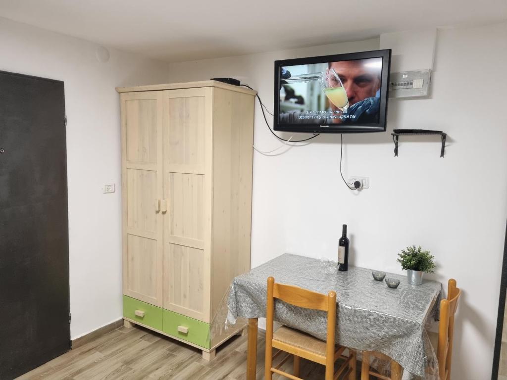 una sala da pranzo con tavolo e TV a parete di "פנינת עין כרם" יחידות ורד ואגוז a ‘En Kerem