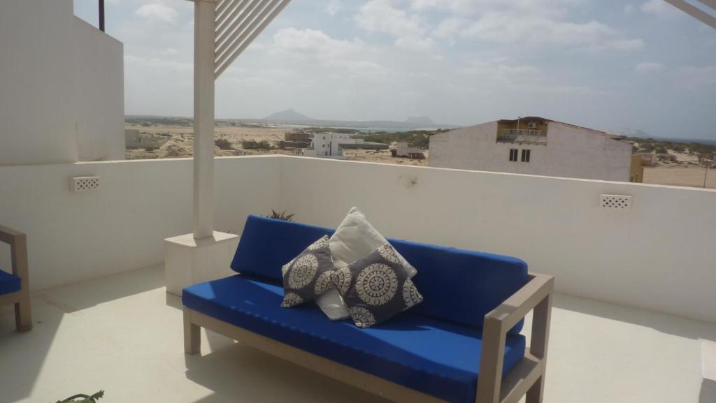 un sofá azul con 2 almohadas en el balcón en App Rosanna, Estoril Beach, 2steps from the sea, Free Wi-Fi & AC en Sal Rei