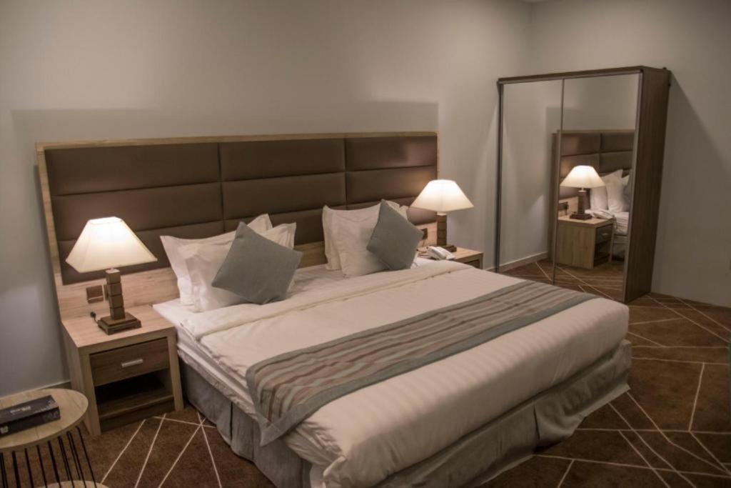 a bedroom with a large bed with two lamps and a mirror at Fiori Hotels in Taif