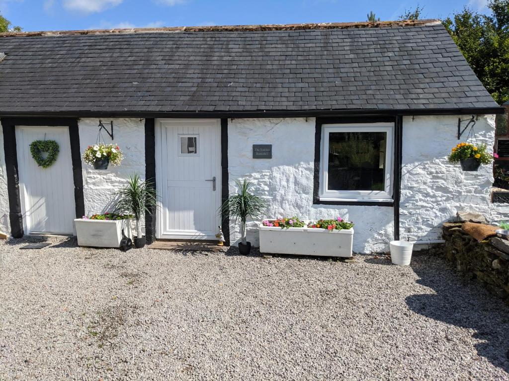 um chalé branco com dois vasos de flores em frente em The Stables - Bankshill em Lockerbie