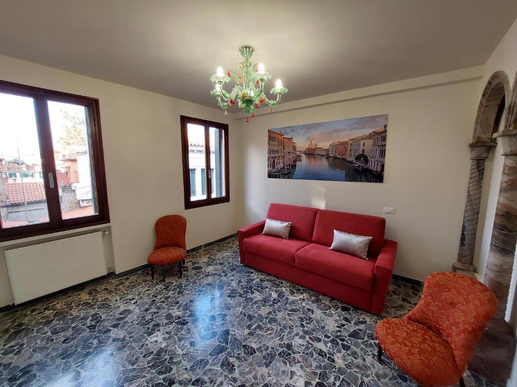 sala de estar con sofá rojo y 2 sillas en Residenza Donini in Venice Suite 1, en Venecia
