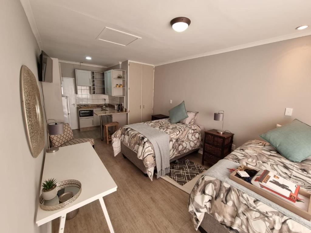um quarto com 2 camas, uma mesa e uma cozinha em THE SPARE BEDROOM Unit 2 em Harrismith