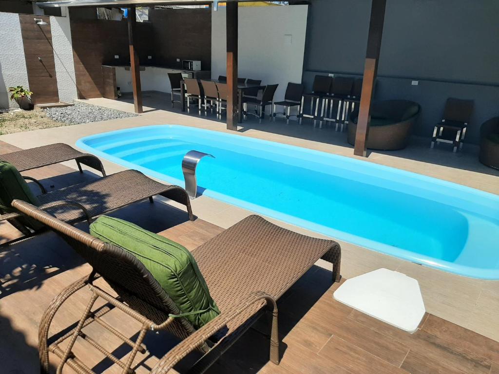 uma grande piscina com cadeiras e uma mesa em Pousada Praia Cia, Piscina, Centro, Estacionamento, WIFI, Saída até as 16h em Bertioga