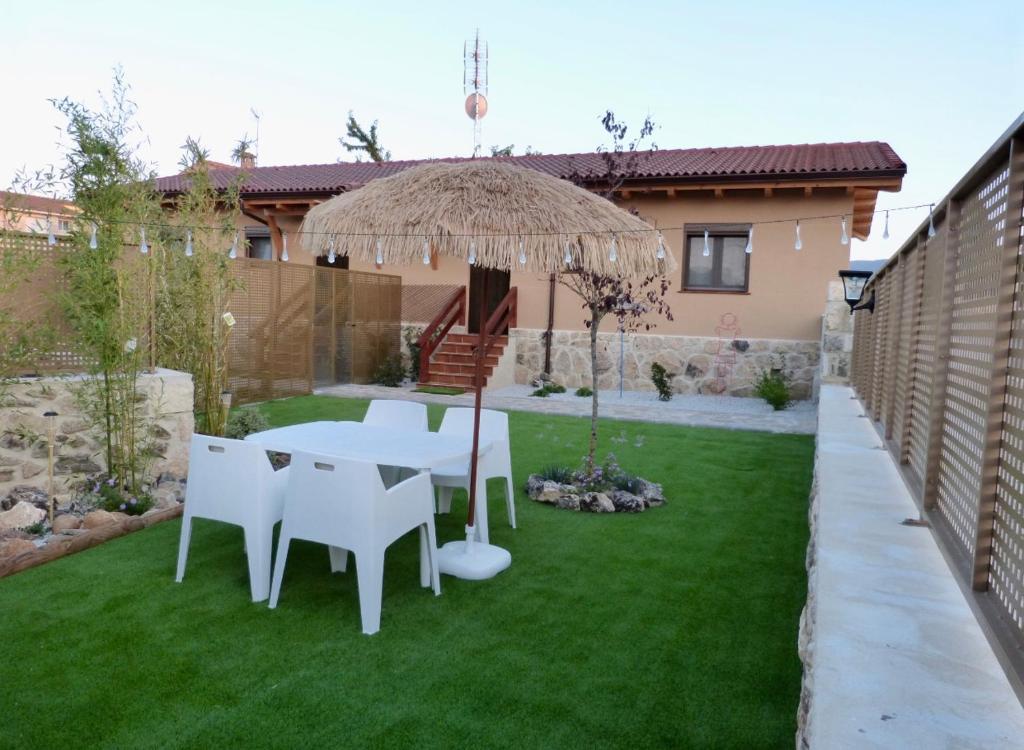 un patio con una mesa y sillas blancas y una sombrilla en Las Casitas de Cerezo 3 en Cerezo de Abajo