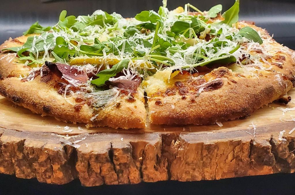 a pizza sitting on top of a wooden cutting board at Inn at the Falls in Bracebridge