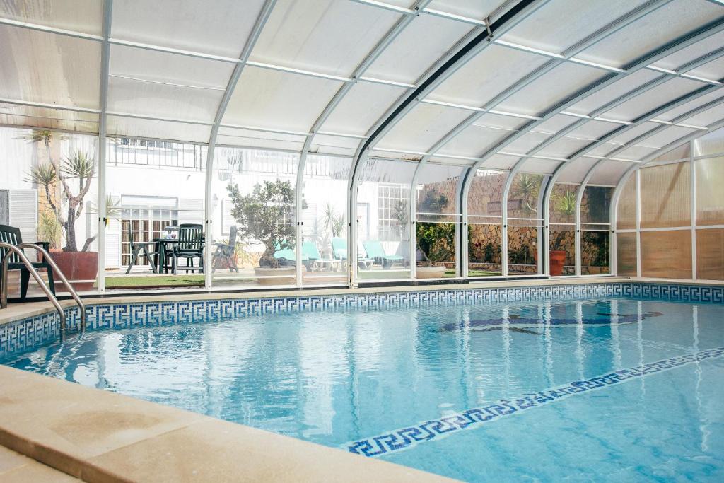 an indoor swimming pool with a large glass ceiling at Dii Beach House - Casa de Férias com piscina interior aquecida in Torres Vedras