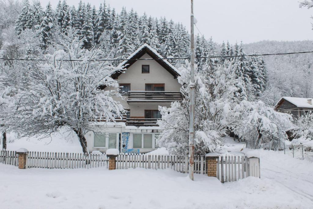a house covered in snow with a fence and trees at Planinska kuća za odmor Vuković in Podgrab