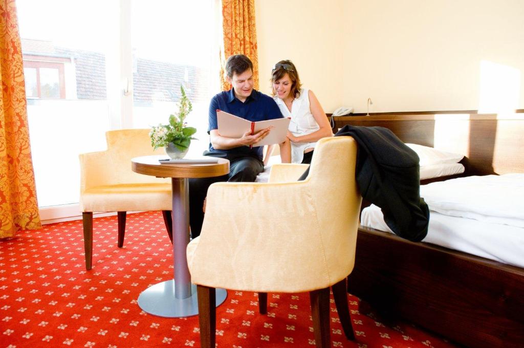 Un uomo e una donna seduti a un tavolo in una stanza d'albergo di Hotel Öhlknechthof a Horn