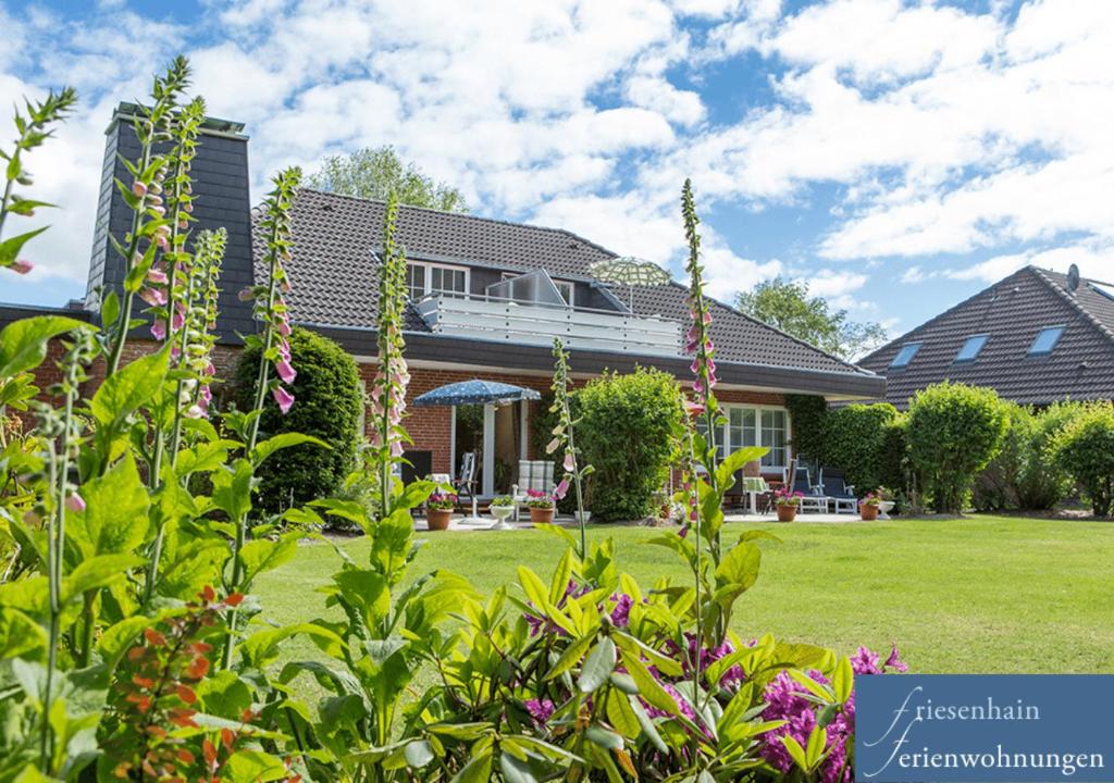 a house with a yard with plants and flowers at Friesenhain Ferienwohnungen in Sankt Peter-Ording