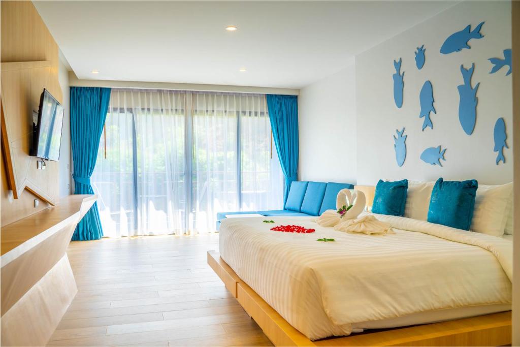 a bedroom with a large bed with blue accents at Golden Paradise Hotel - SHA PLUS in Karon Beach