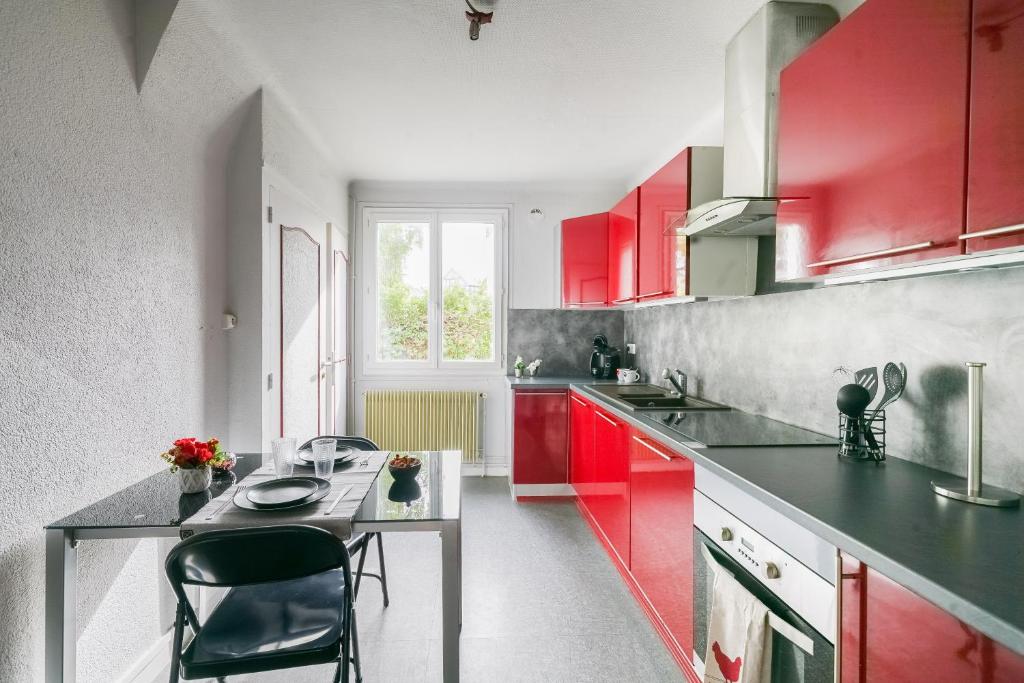 a kitchen with red cabinets and a table in it at Le Berry - Maison de ville - Parking privé in Bourges
