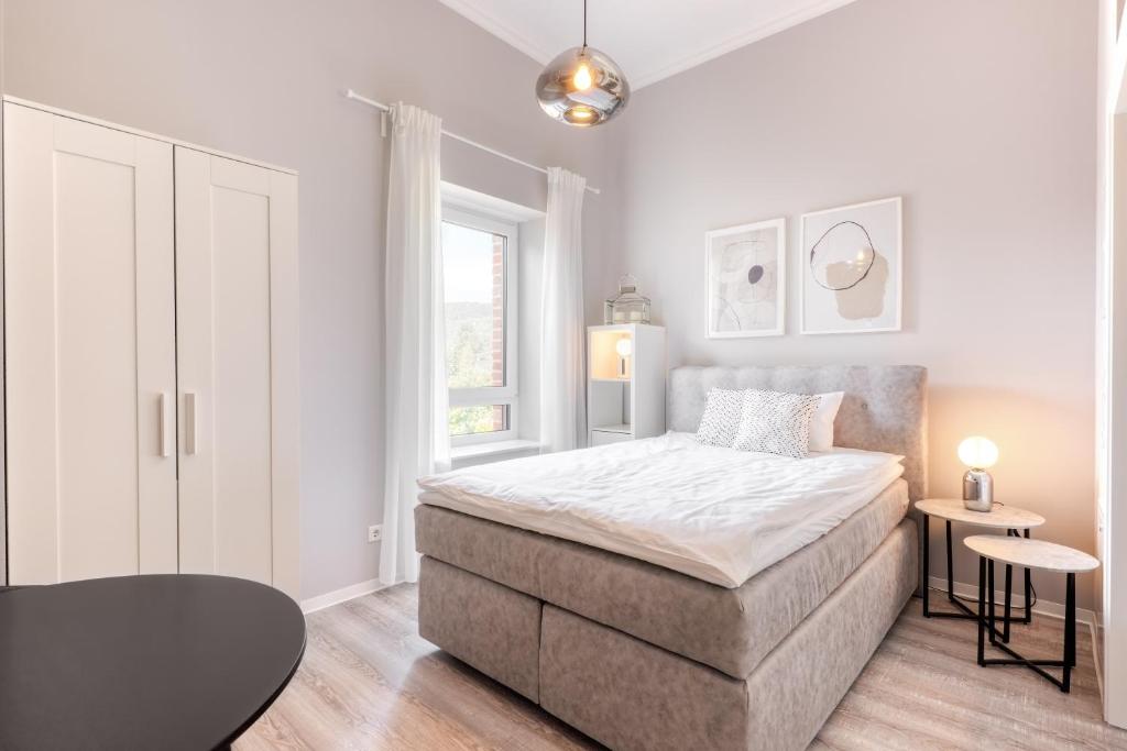 a white bedroom with a bed and a window at Apartment Homely in Porta Westfalica