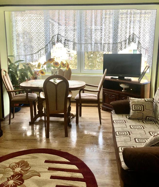 a living room with a table and chairs and a television at La SYMO apartament STRAJA Lupeni in Lupeni