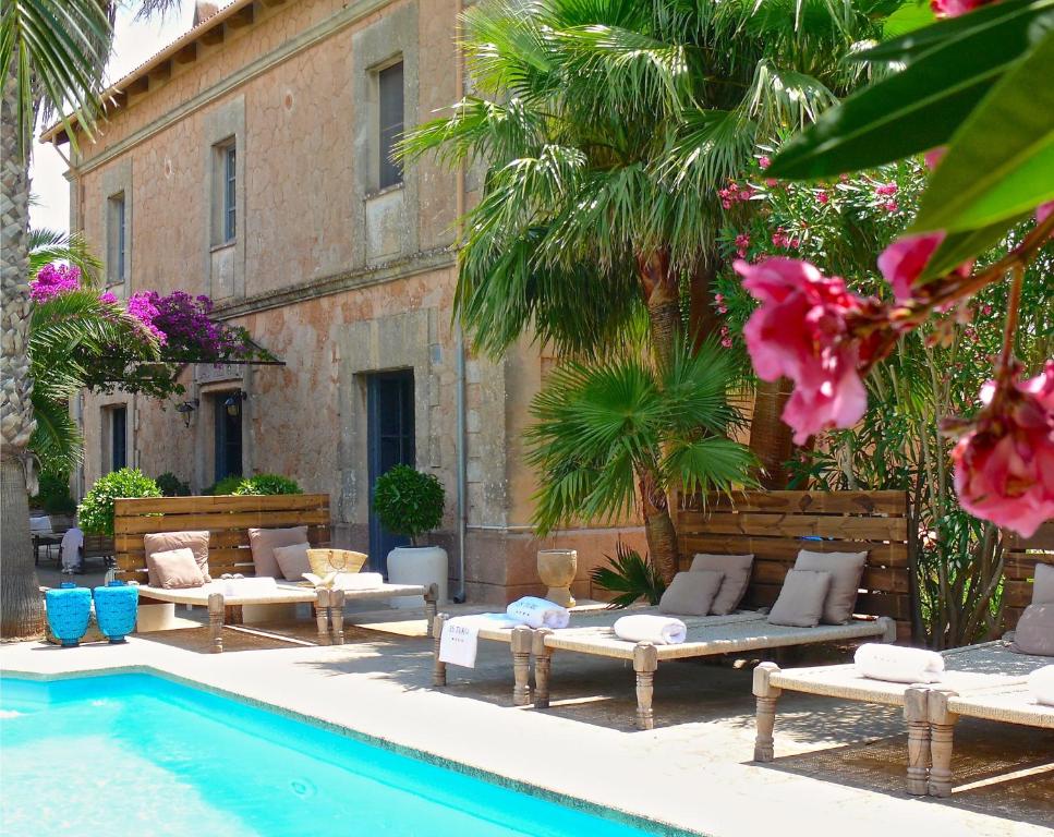 a pool with chaises and chairs next to a building at Villa Station by Cassai in Ses Salines