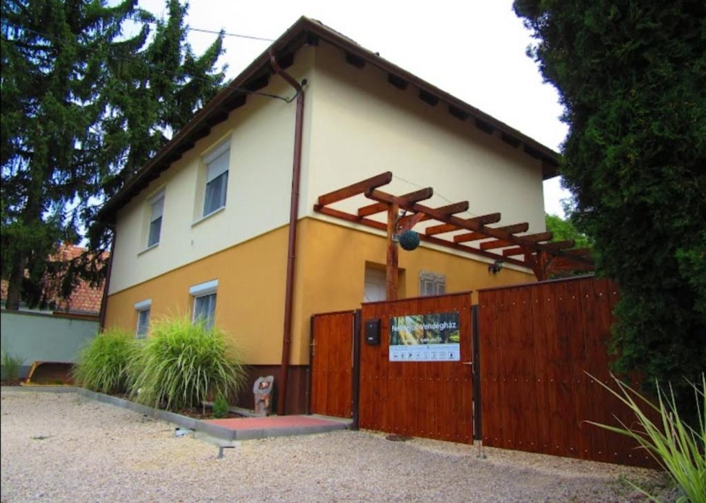 une maison avec une clôture en bois devant elle dans l'établissement Bakonybél Nefelejcs Vendégház, à Bakonybél