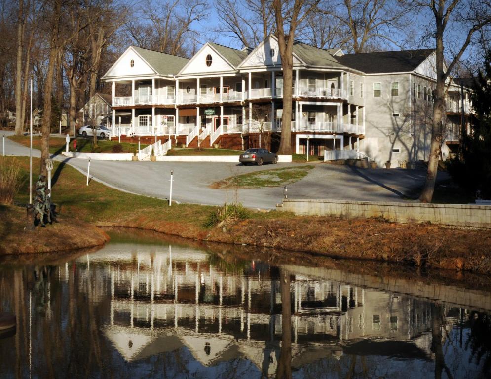 ein großes weißes Haus mit einer Reflexion im Wasser in der Unterkunft Acorn Hill Lodge and Spa in Lynchburg