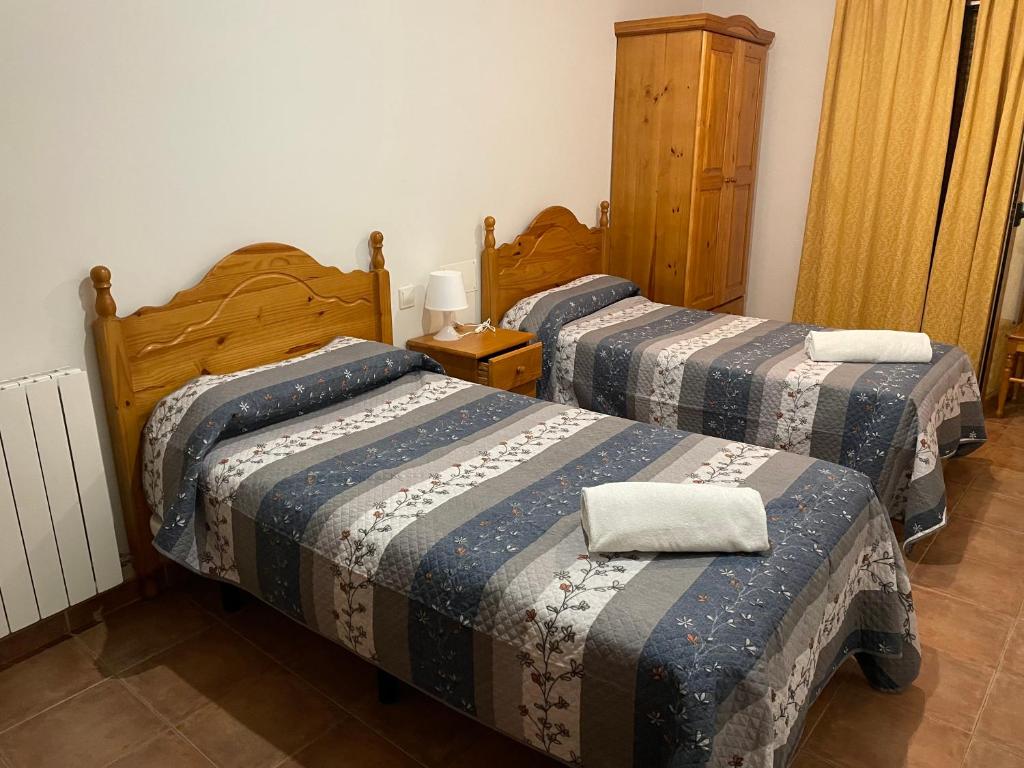 1 dormitorio con 2 camas y mantas azules y grises en Hostal Matias, en Abades