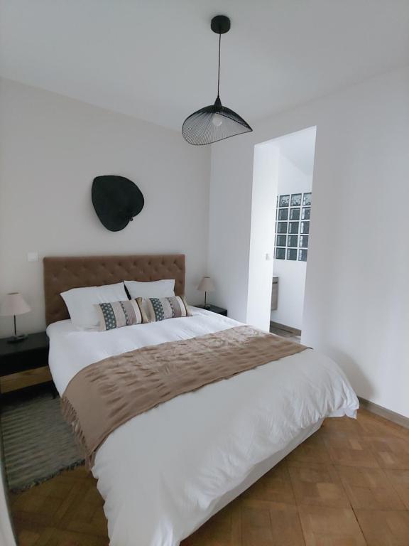 a bedroom with a large bed with white walls at LA BERGE in Amiens